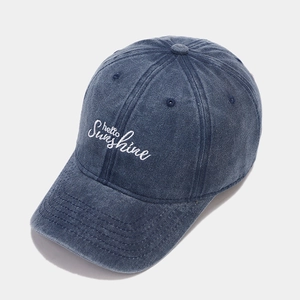 Detailed view of Hello Sunshine white embroidery on a navy washed denim baseball cap