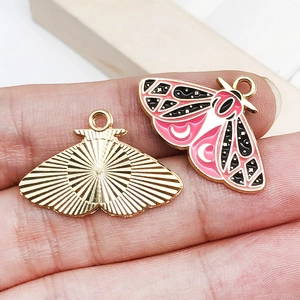 Detail of pink and black enamel moth charm with gold metal texture and hanging loop