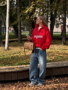 Outdoor street style featuring a red California graphic sweatshirt with a half-zip collar