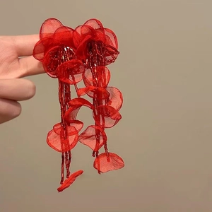 Close-up detail of vintage red fabric flower earrings with elegant long bead tassels