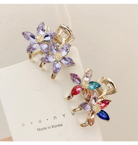 Macro shot of small gold floral hair claws with colorful crystal petals on display card