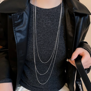 Close-up of a three-layer silver tassel necklace with delicate beads on a black jacket