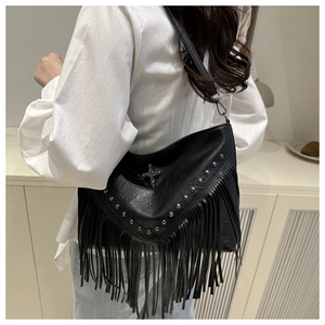 Detail shot of black fringe crossbody bag with silver studs and crucifix charm on model