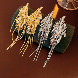 Detail of elegant gold and silver wheat tassel earrings with a metallic flowing leaf design