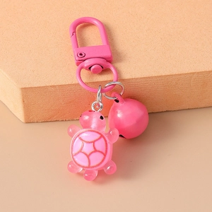 Close-up of pink resin turtle keychain with matching pink bell and metal clasp detail