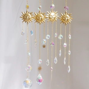 Detail of golden sun catcher with crystal prisms reflecting rainbow light on grey fabric