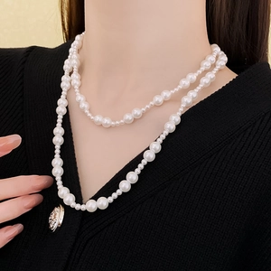 Gros plan d'un collier de perles blanches à double rangée avec fermoir OT sur pull noir