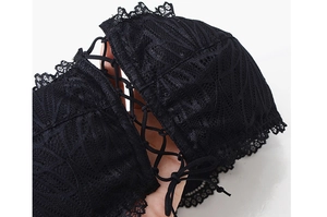 Detailed close-up of black lace fabric with intricate eyelash trim and strapless design
