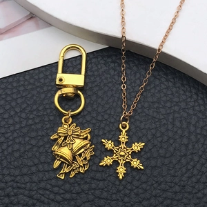 Detailed close-up of gold bell bow keychain and snowflake necklace on black leather