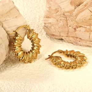 Luxury gold geometric textured hoop earrings with spiral design on stone background