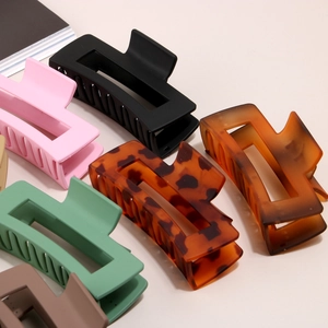 Flat lay of matte rectangular hair claw clips in various colors like black and amber
