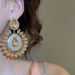Macro shot of luxury oversized champagne teardrop crystal floral earrings on a model