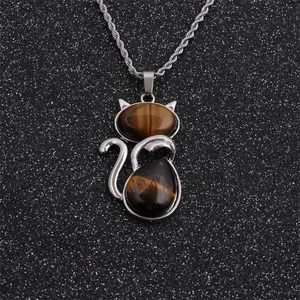 Close-up of cat pendant with tiger eye stones and silver twist chain on black background