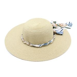 Close-up of wide brim straw hat featuring tropical floral ribbon and white pearl accents