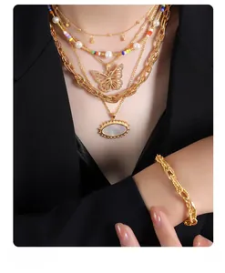 Detail of layered gold-plated necklaces with butterfly and mother-of-pearl charms on model