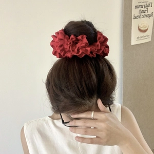 Detail showing a large burgundy satin floral scrunchie on a woman's hair with French style
