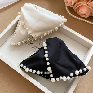 Détail de pinces à cheveux triangulaires en satin noir et blanc ornées de perles