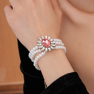 Gros plan du bracelet en perles multicouches avec pierre rose et cristaux floraux