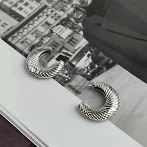 Detailed view of silver-toned C-shaped textured earrings on a fashion magazine background