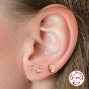 S925 sterling silver skull stud earring with diamonds shown on ear in gold finish