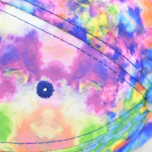 Close-up of colorful tie-dye fabric texture with blue reinforced stitching and eyelet