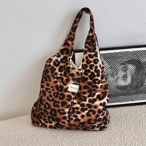 Detailed close-up of leopard print canvas tote bag leaning against a minimalist white wall