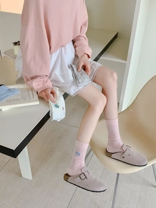 Close-up of pink knitted crew socks featuring delicate blue flower embroidery detail