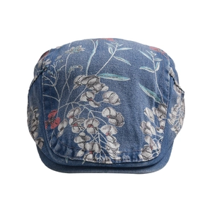 Detailed macro shot of vintage floral print on washed blue denim newsboy cap