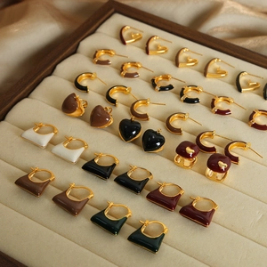 Chic gold-plated geometric enamel earrings in various colors on a velvet tray display