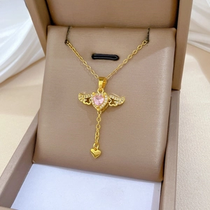 Makroaufnahme der Goldkette mit rosa Herzstein und beweglichen Engelsflügeln auf Samt