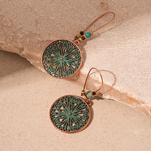 Close-up of vintage bronze flower earrings with green enamel and colorful beads on stone