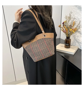Detail of khaki plaid wool shoulder bucket bag shown worn by model in a minimalist setting