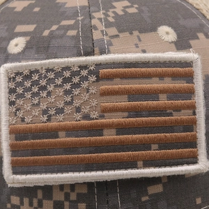 Detailed close-up of tactical desert camo baseball cap with embroidered US flag patch