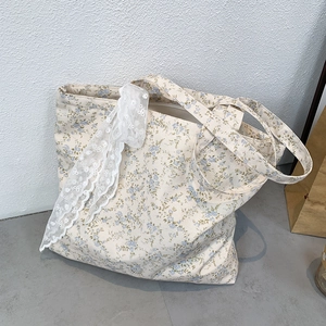 Detailed shot of beige floral canvas tote with blue flower patterns and white lace bow