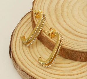 Detail of gold J-shaped earrings with double-row micro-inlaid white cubic zirconia