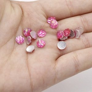Close-up of pink fish scale resin cabochons with AB rainbow finish held in hand