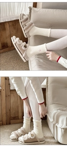 Close-up of fluffy khaki slippers with double buckle straps and warm white socks
