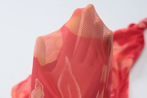 Vue détaillée macro montrant la texture du tissu en maille rouge respirant et l'imprimé