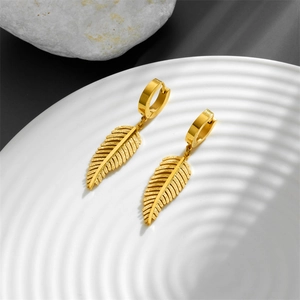 Elegant gold leaf dangle earrings with frosted texture on a minimalist white stone background