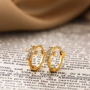 Gros plan de boucles d'oreilles croix plaquées or 18 carats avec zircons sur soie