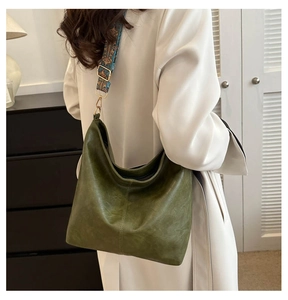 Detail of vintage green hobo bag featuring a colorful bohemian embroidered strap