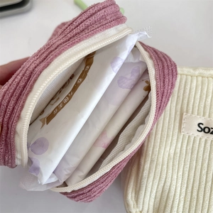 Detail of corduroy makeup bag showing zipper and textured fabric in pink and cream