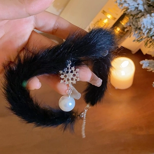 Détail du ras du cou en fourrure noire avec pendentif flocon argenté et perle blanche