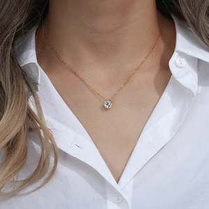 Collier doré avec pendentif couronne en zircon blanc porté par un mannequin sur chemise