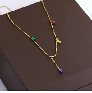 Close-up of gold beaded necklace with colorful red green yellow and purple crystal pendants