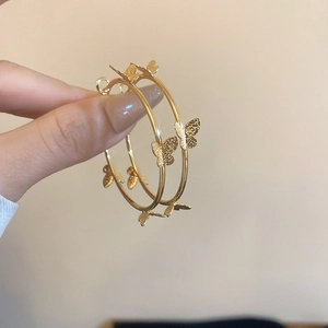 Detail shot of golden butterfly hoop earrings with frosted texture and elegant design
