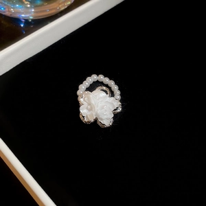 Macro shot of silver ring featuring a white 3D flower surrounded by small pearls