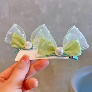 Close-up of light green bow hair clips with organza layers and white faux pearls