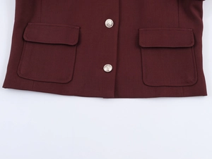Detail view of burgundy tweed jacket hem featuring silver metal buttons and flap pockets