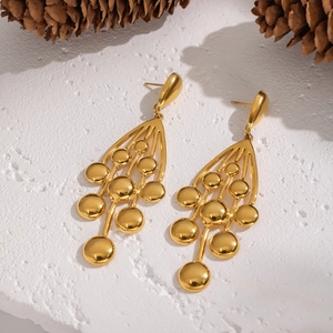 Vue détaillée de boucles d'oreilles grappes dorées sur une surface texturée avec pommes de pin